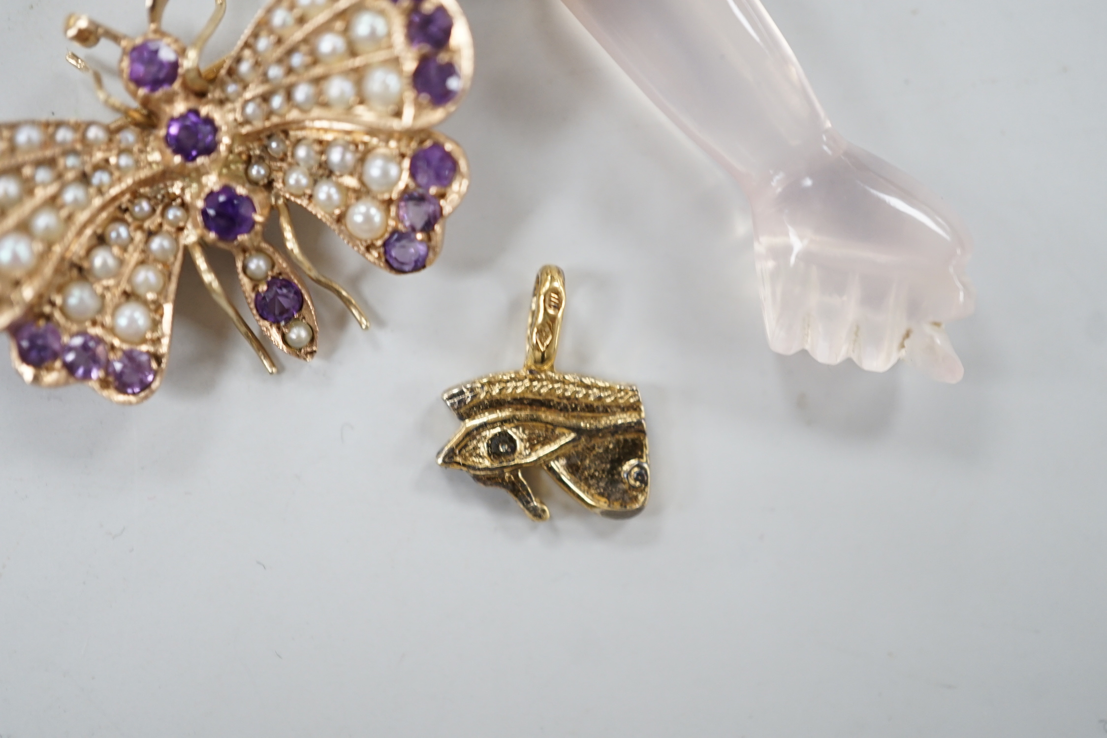 A modern 9ct gold, amethyst and seed pearl cluster set butterfly brooch, width 32mm, together with two charms including arm and fist.